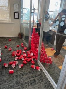 Lindsay and Jess look down in horror as their solo cup wall has caved in